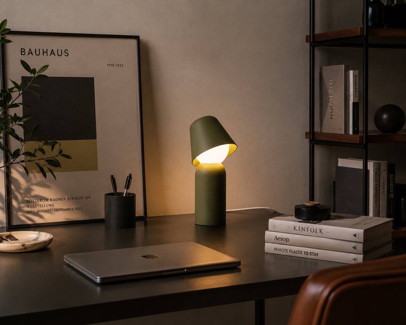 JUNEE olive directional table lamp lighting a dark desk beside a Bauhaus poster.