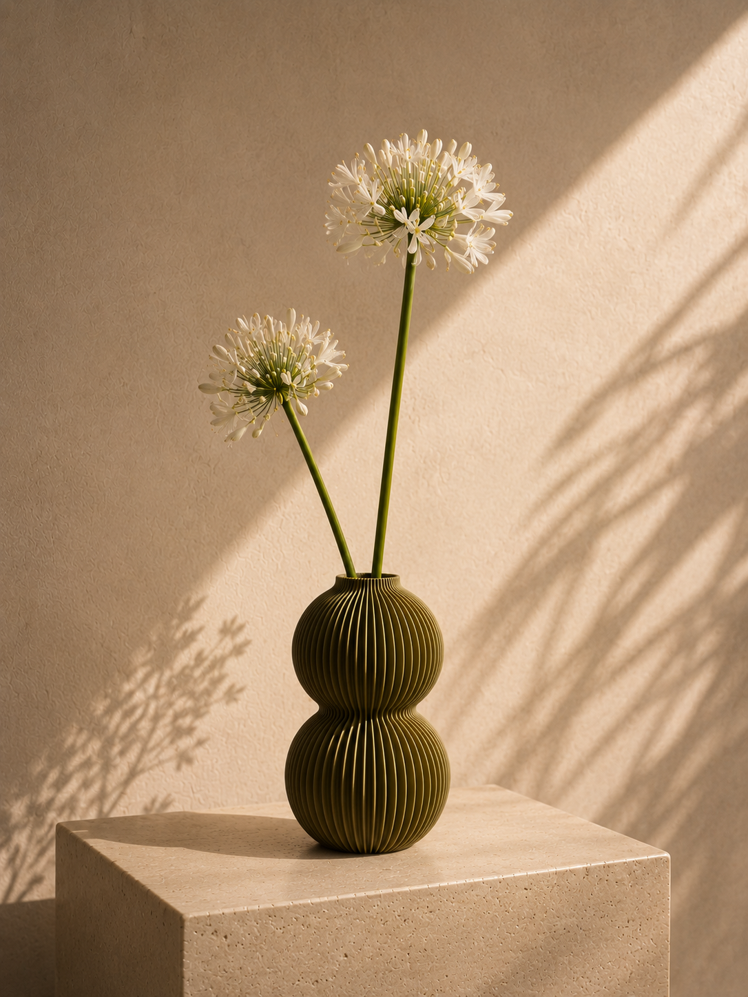 Olive ribbed Orb vase on a concrete pedestal in warm light.